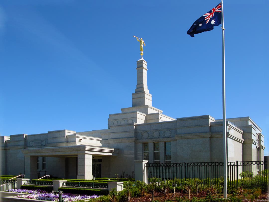 Perth Australia Temple exterior with Angel Moroni, Australian flag, and gardens.