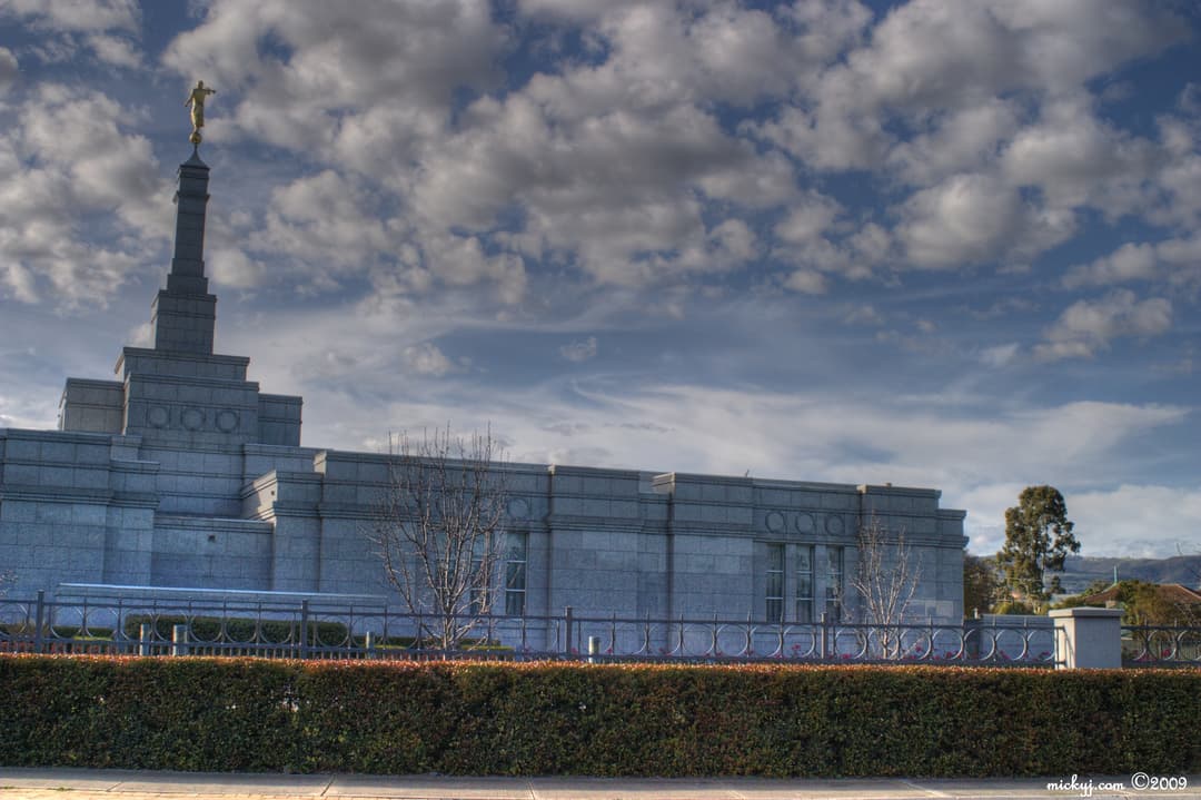 Side view of Perth Australia Temple with Angel Moroni under cloudy sky.