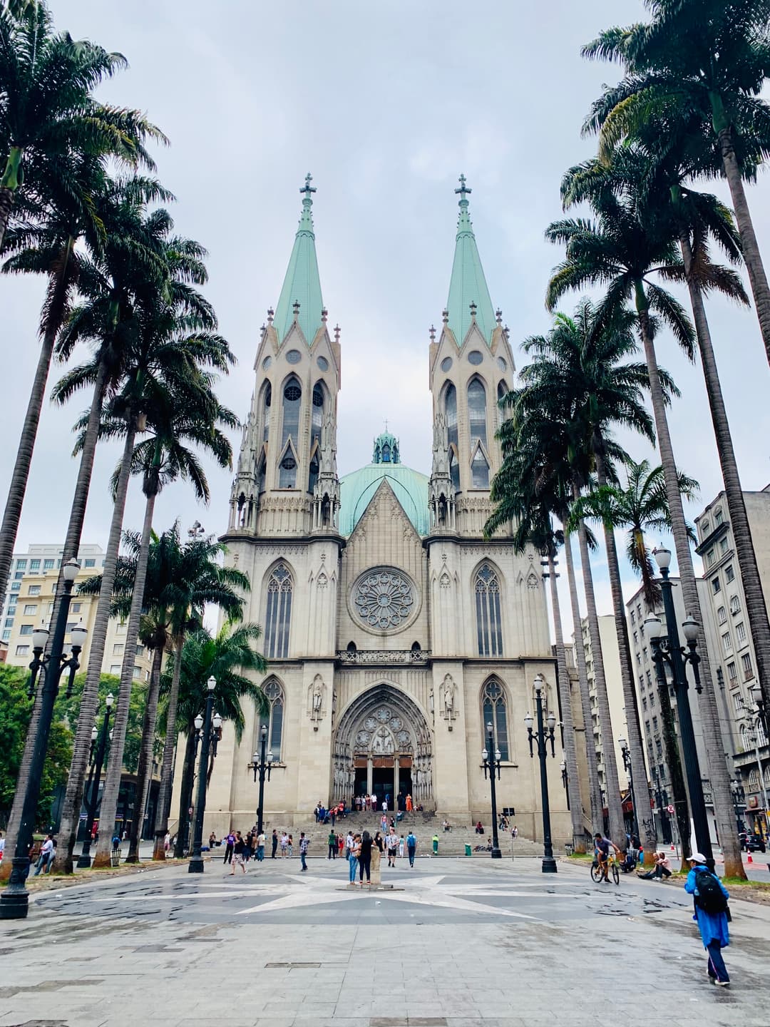 Front view of Catedral da Sé framed by tall palm trees in Praça da Sé.