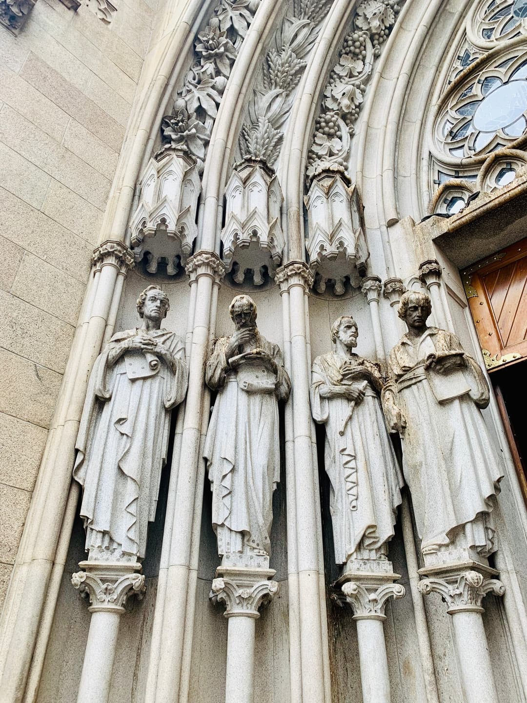 Carved stone statues flanking the Gothic Revival portal of Catedral da Sé.