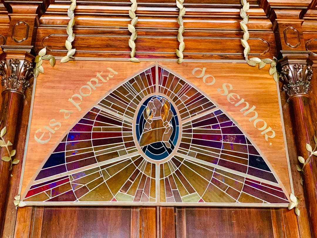 Stained glass panel and inscription reading "Eis a porta do Senhor.