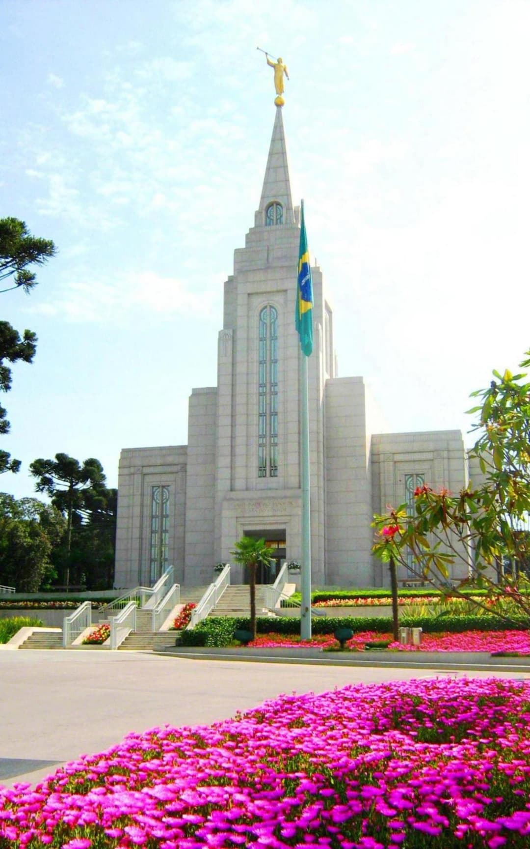 Front view of the Curitiba Brazil Temple with pink flowers in the foreground.