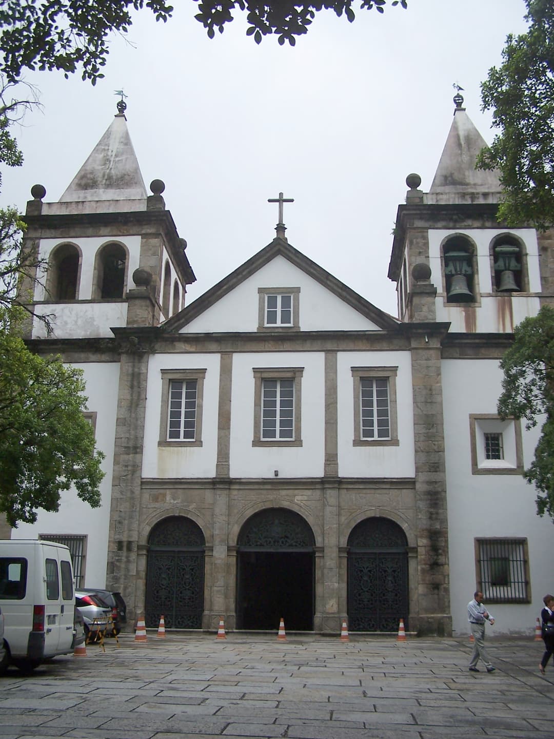 Frontal view of the church facade with twin spires on an overcast day.