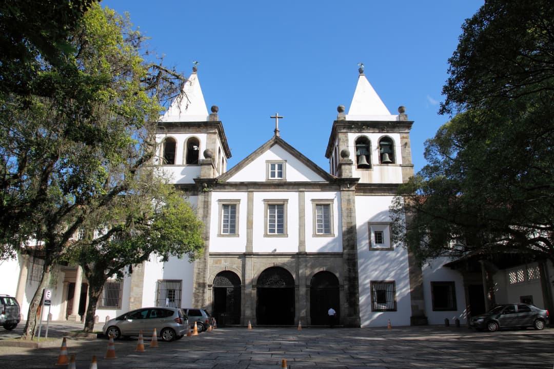 Front view of the white colonial church facade under a clear blue sky.