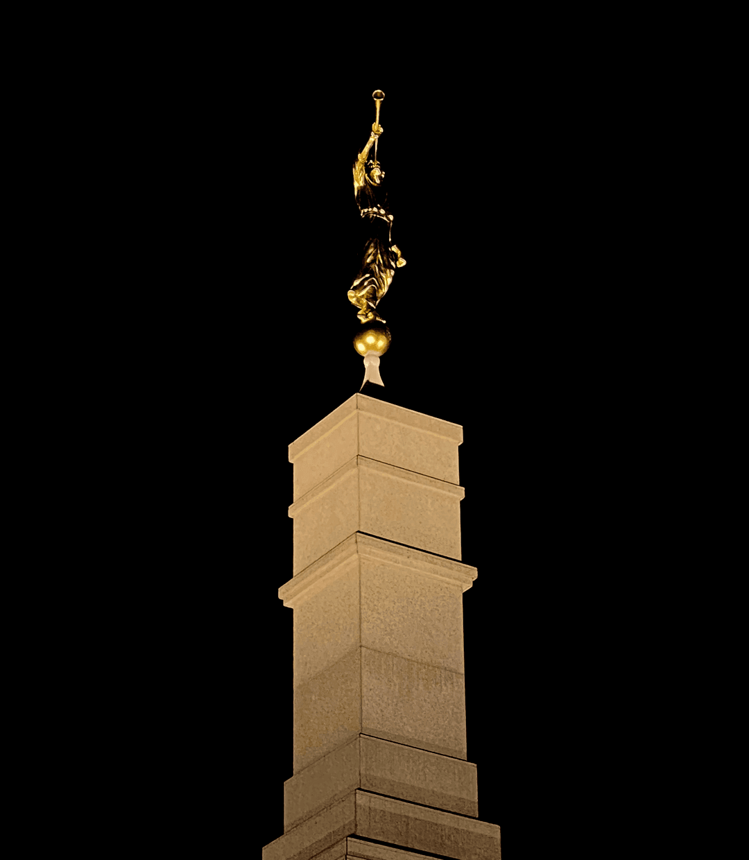Close-up of the Angel Moroni statue atop the central spire at night.