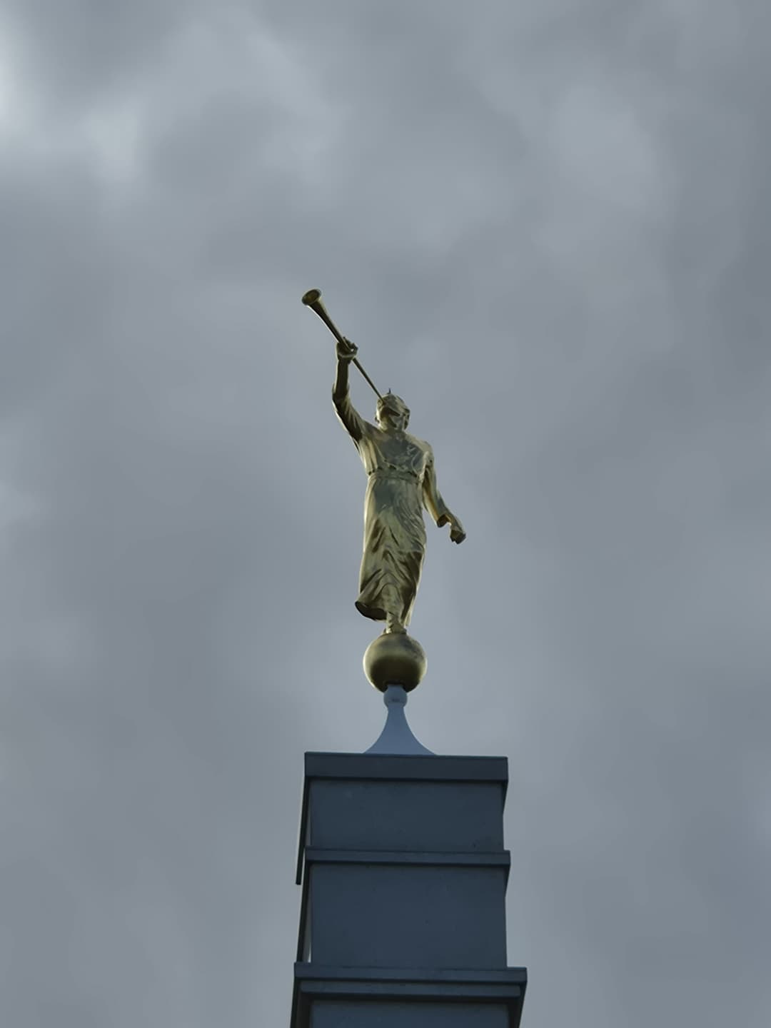Golden Angel Moroni statue atop the spire against an overcast sky.