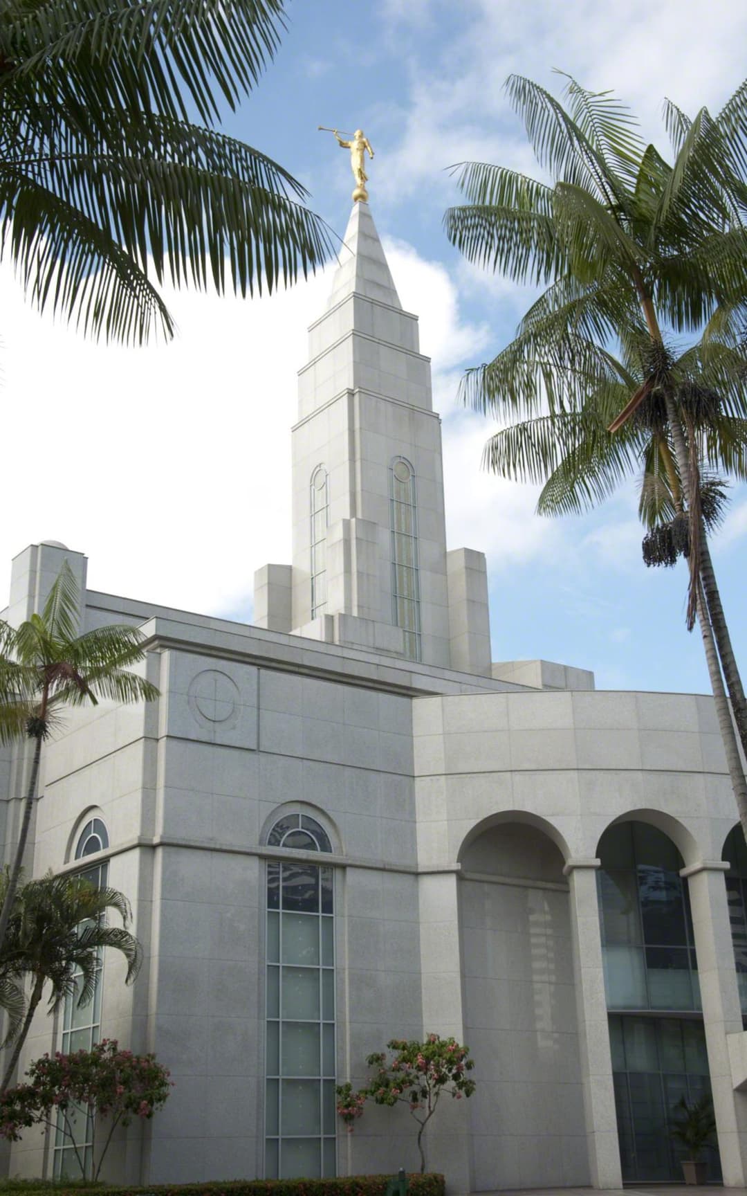 Low-angle view of the Recife Brazil Temple spire framed by palm trees.