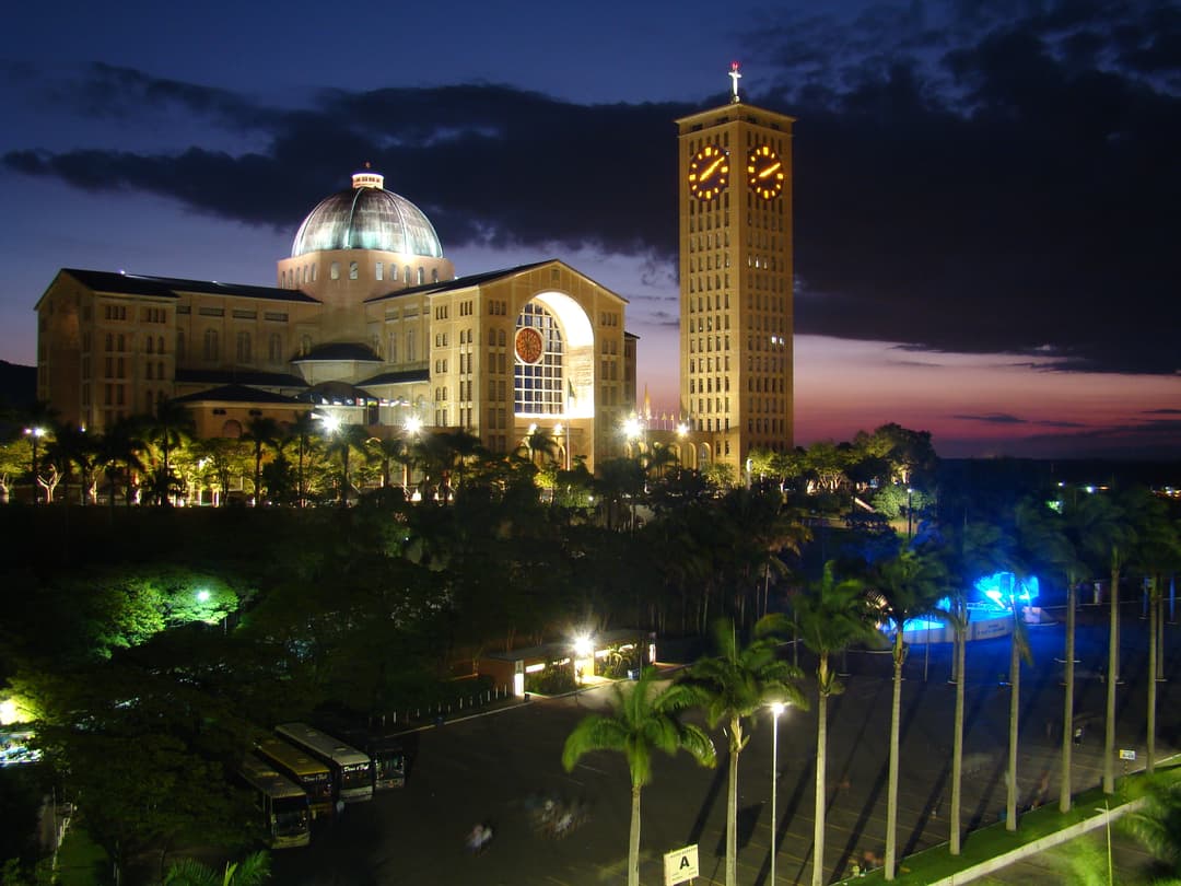 Exterior view of the illuminated Basilica of Aparecida at twilight.