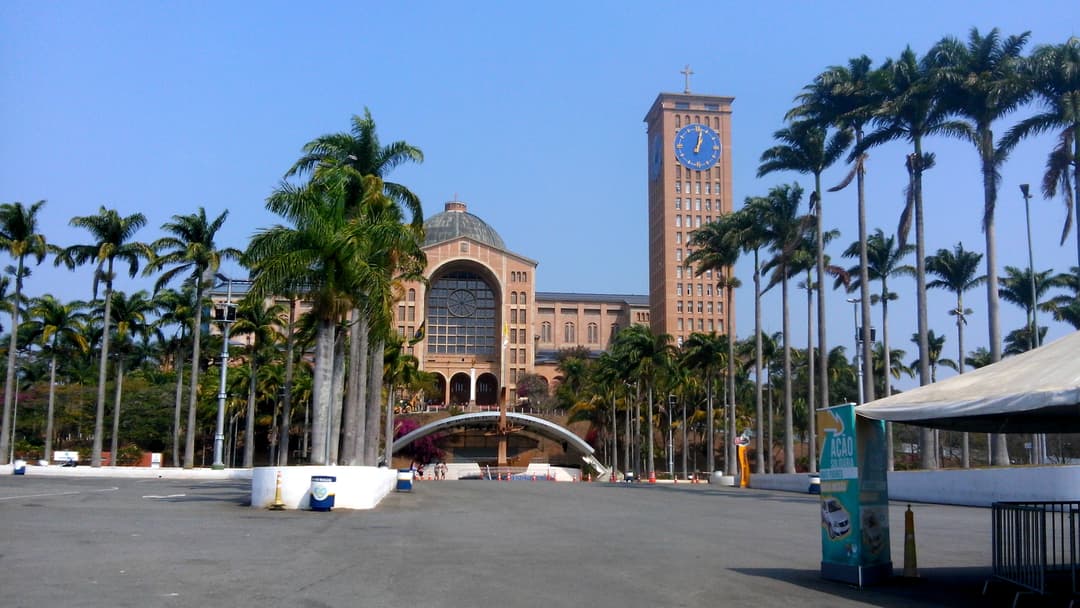 Exterior view of the sanctuary facade, clock tower, and palm-lined plaza.