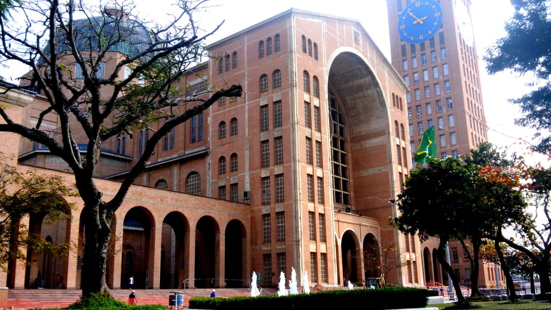 Exterior view of the brick façade, monumental arch, and tall clock tower.