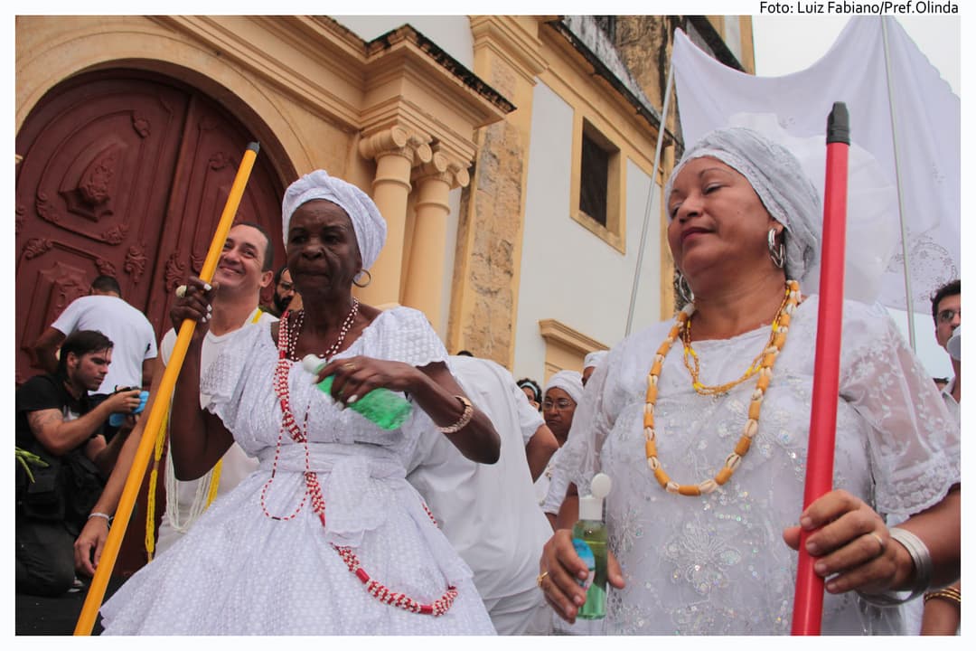 People in white outside a building.