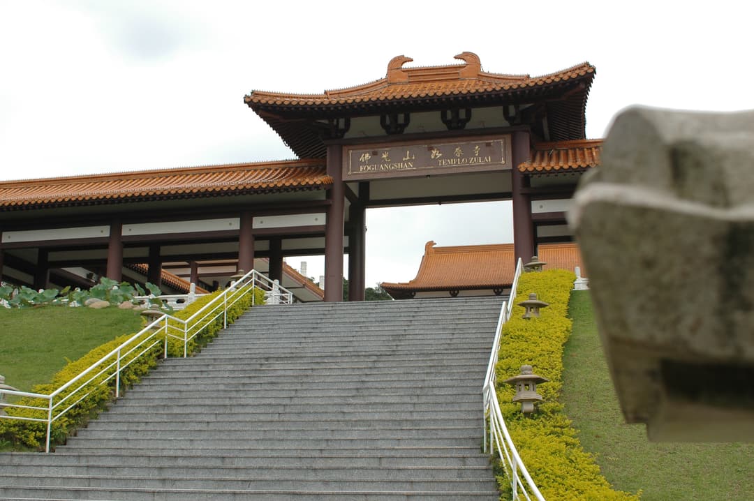Low-angle view of the grand entrance gate and stone stairs at Templo Zu Lai.