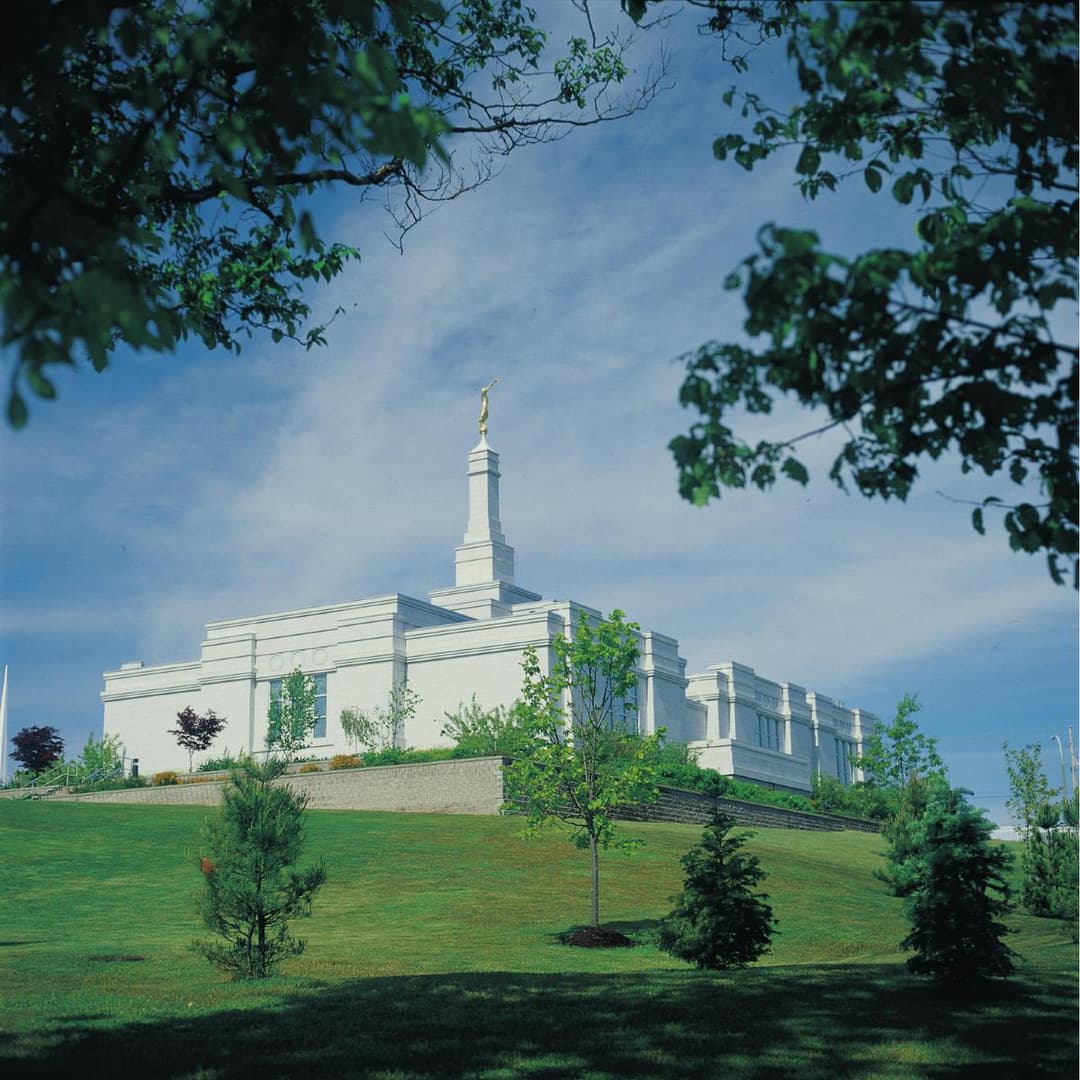 Halifax Nova Scotia Temple exterior, single spire, on a green hill, framed by trees.
