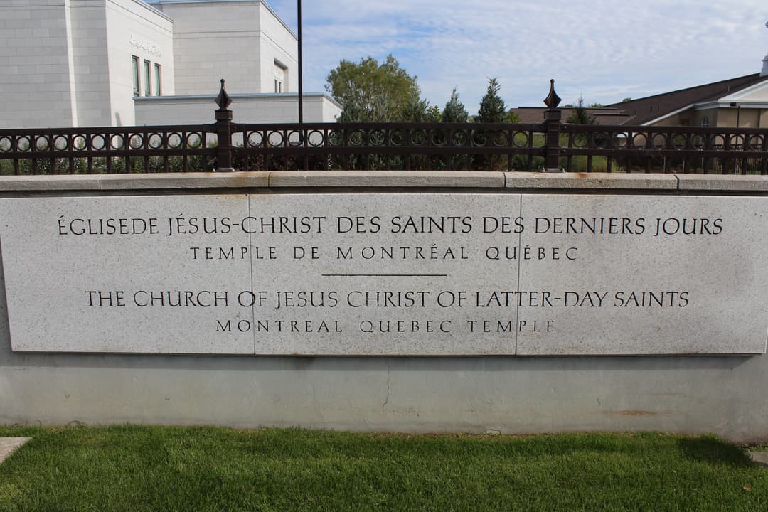 Daytime shot of Montreal Quebec Temple sign, fence, and building.