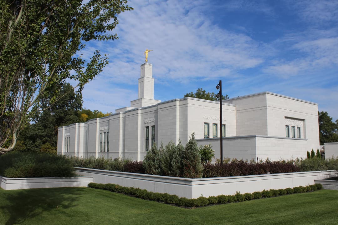 Angled exterior view of Montreal Quebec Temple with Angel Moroni and gardens.