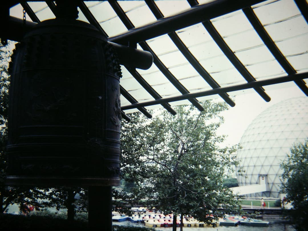 A large Japanese bell with a geodesic dome in the background