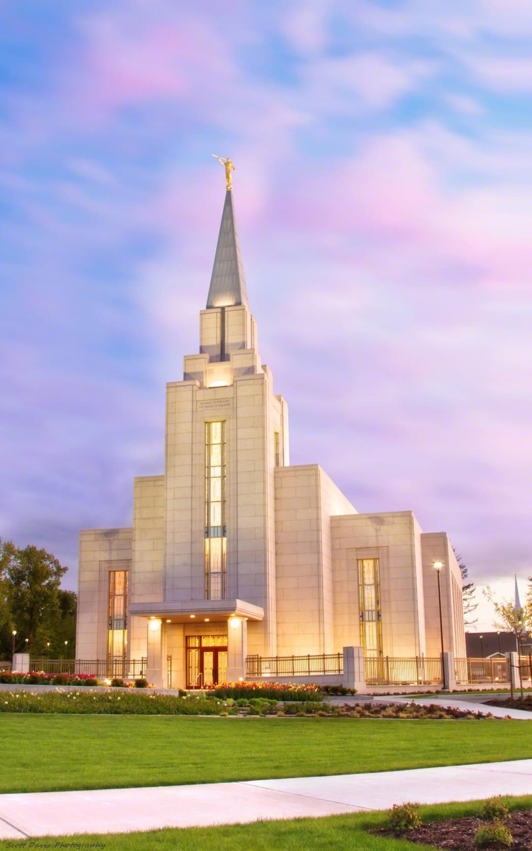 Front view of the illuminated temple and spire at twilight.