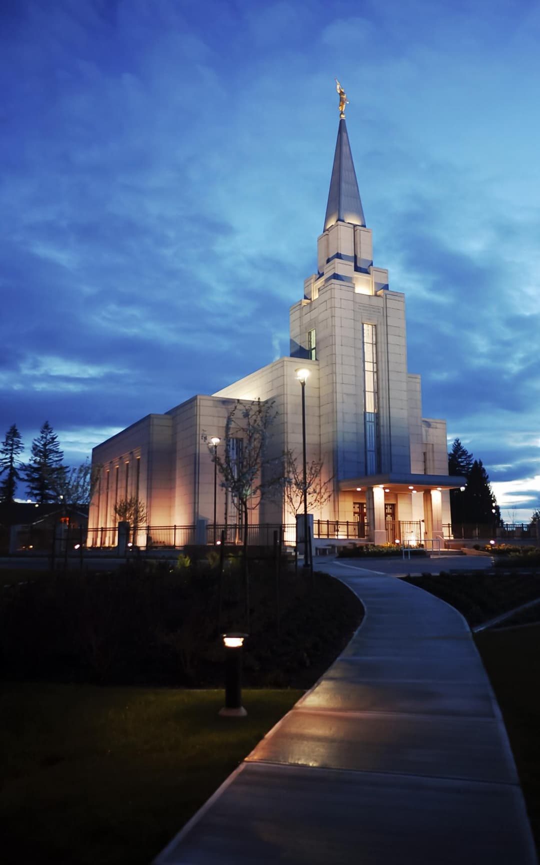 The Vancouver British Columbia Temple with illuminated spire at twilight.