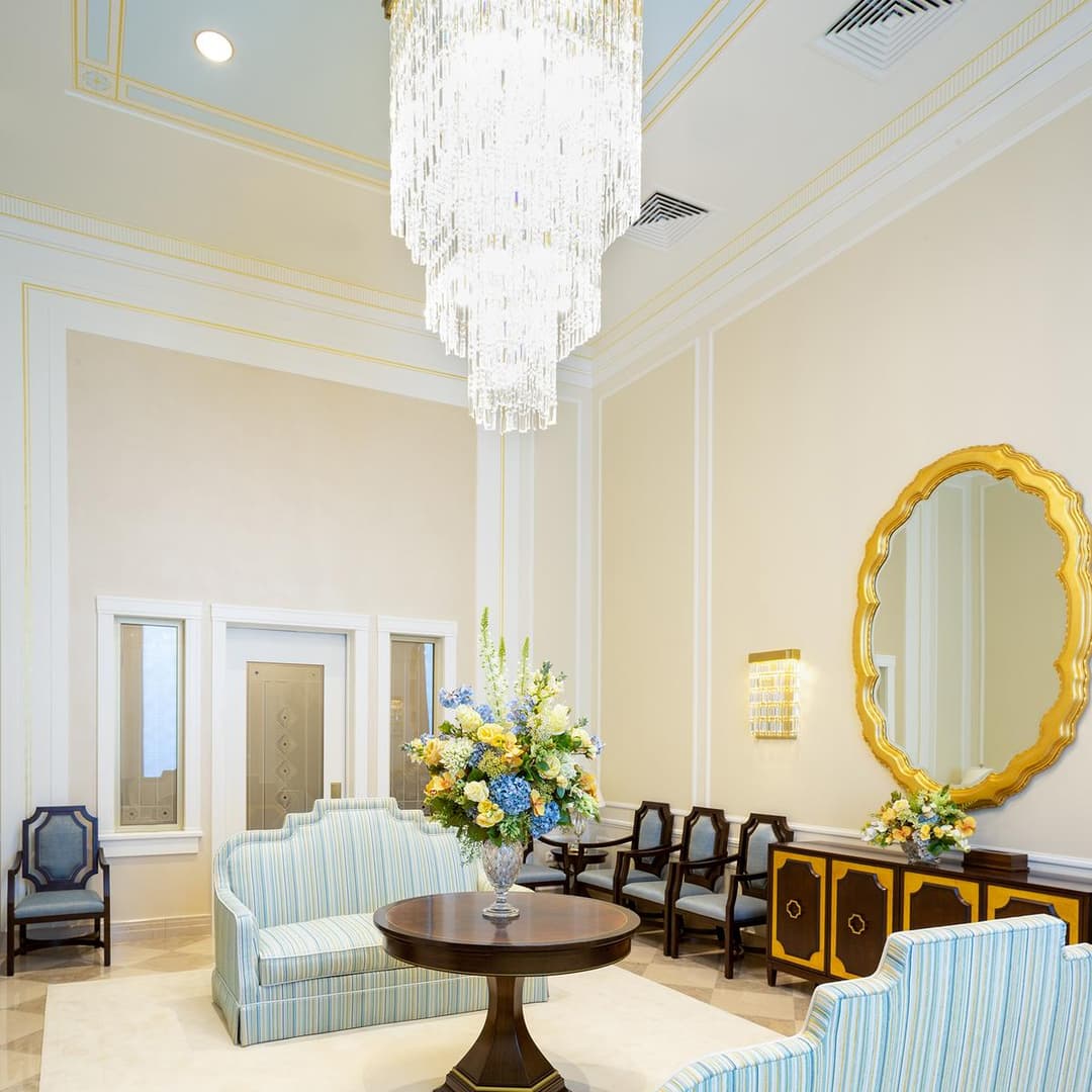 Interior waiting room featuring a tiered crystal chandelier and gold mirror.