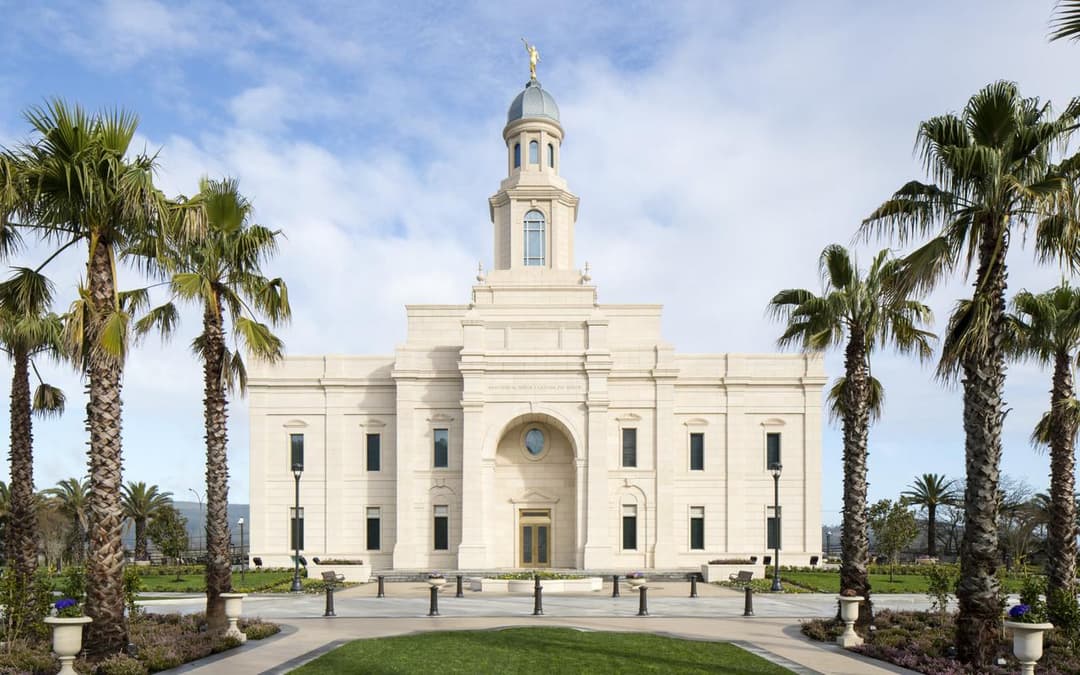 Daytime front view of the Concepción Chile Temple framed by palm trees.