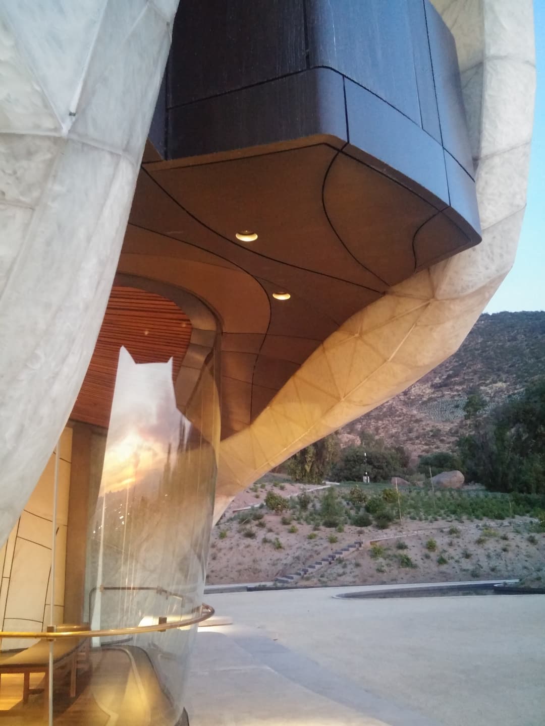 Close-up of the temple's curved translucent facade and plaza at twilight.