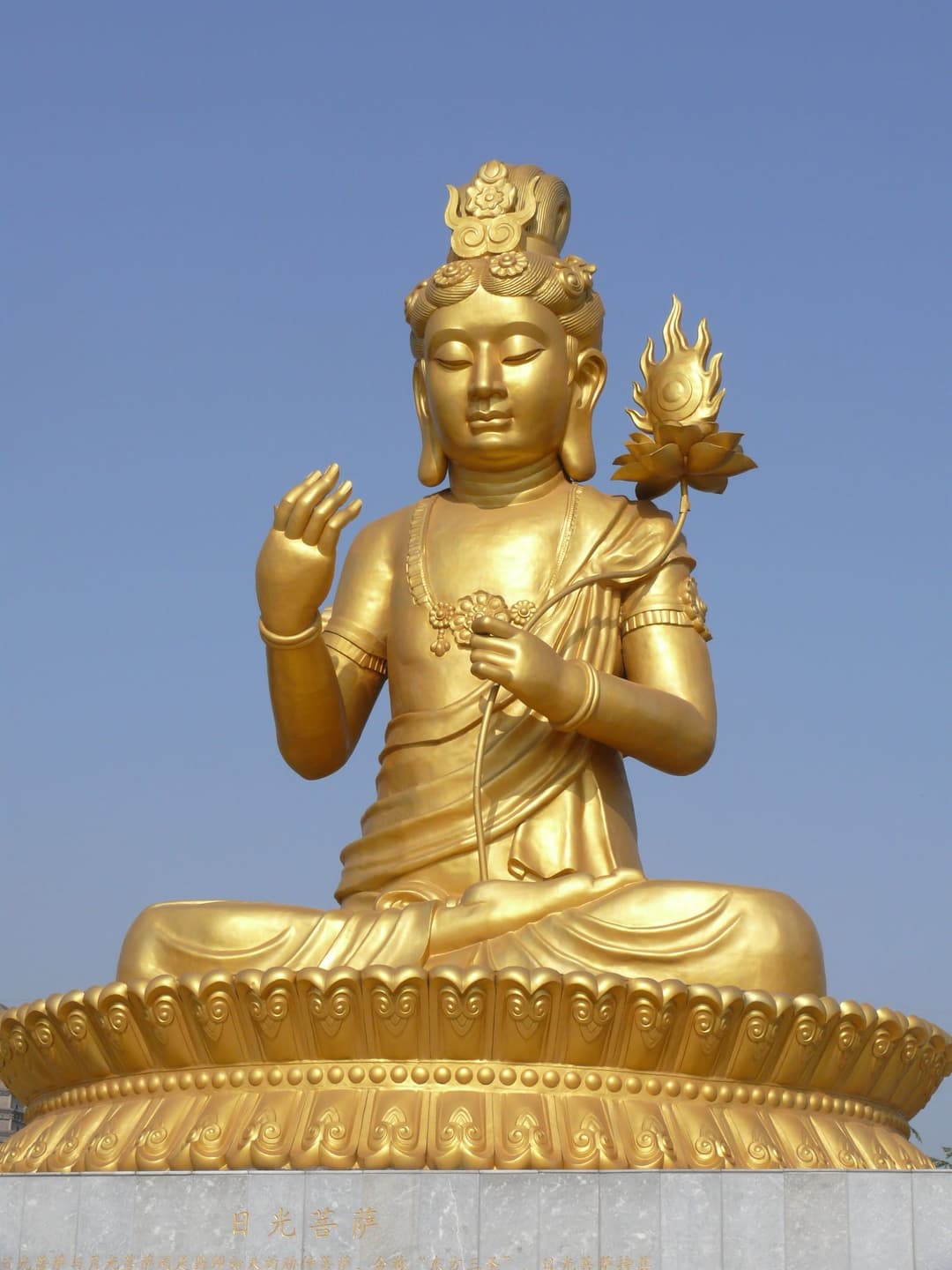 Golden statue of Suryaprabha Bodhisattva seated on a lotus pedestal