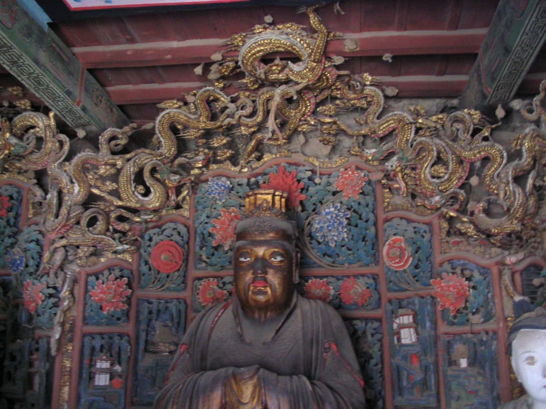 Interior shrine statue with an ornate carved dragon screen in the Hanging Temple