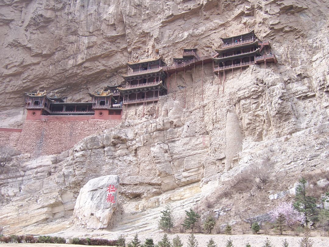 Low-angle view of the Hanging Temple suspended along the sheer cliff face.