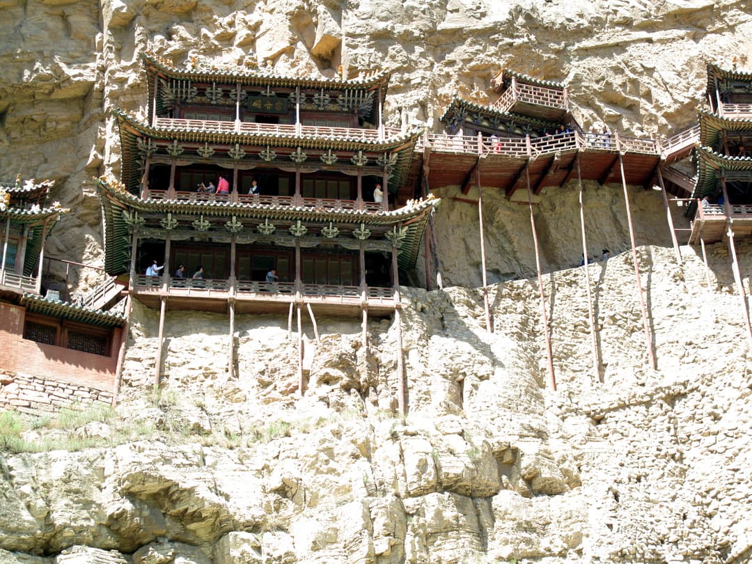Low-angle view of multi-tiered timber pavilions built into the cliff face