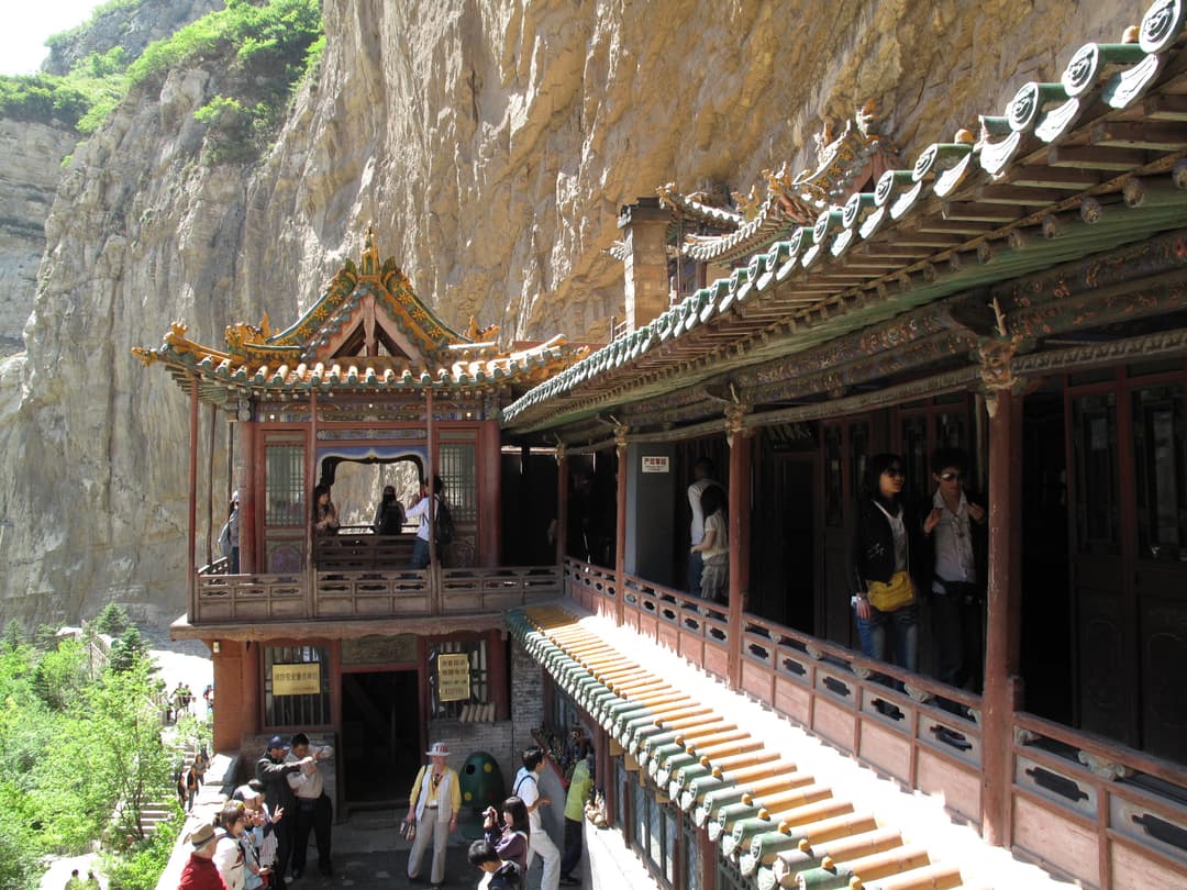 Cliffside timber walkways and pavilion with visitors at the Hanging Temple