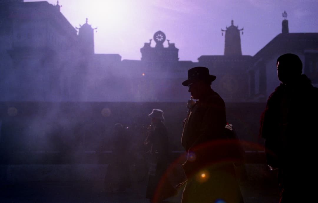 Pilgrims silhouetted in incense smoke before Jokhang Temple