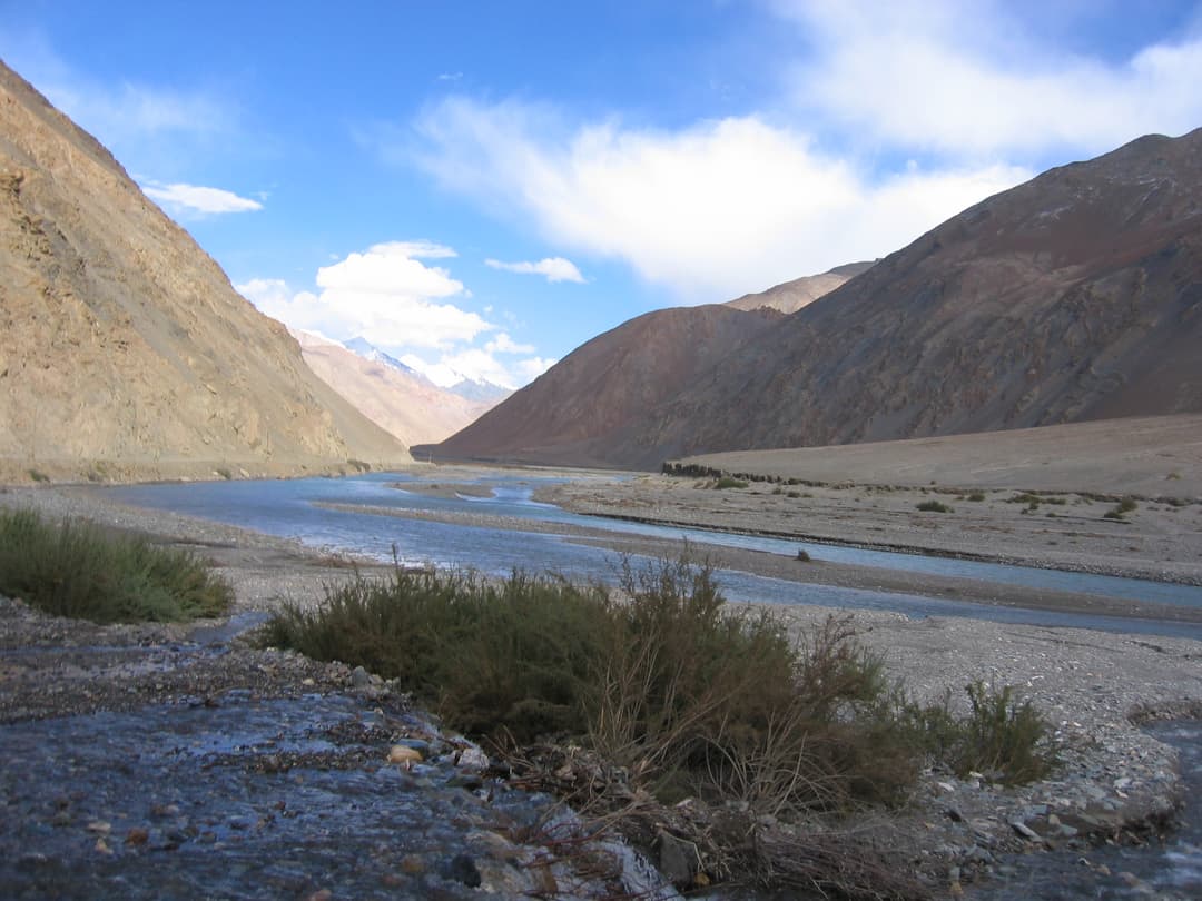 Wide-angle view of a river flowing through an arid Kunlun Mountain valley