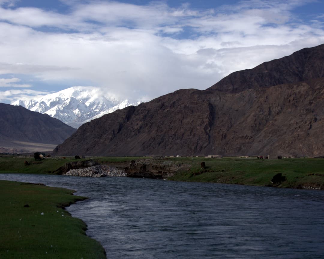 Wide view of a mountain river with snow-capped peak in the distance