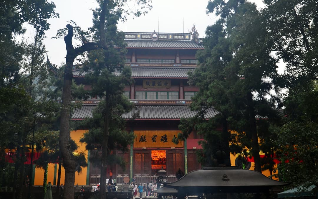 Front exterior view of the Mahavira Hall framed by trees at Lingyin Temple.
