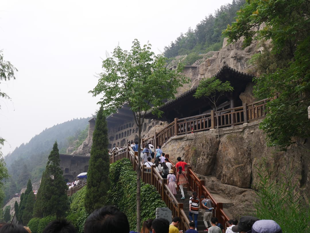 Exterior view of visitors ascending stairs along the cliffside grottoes.