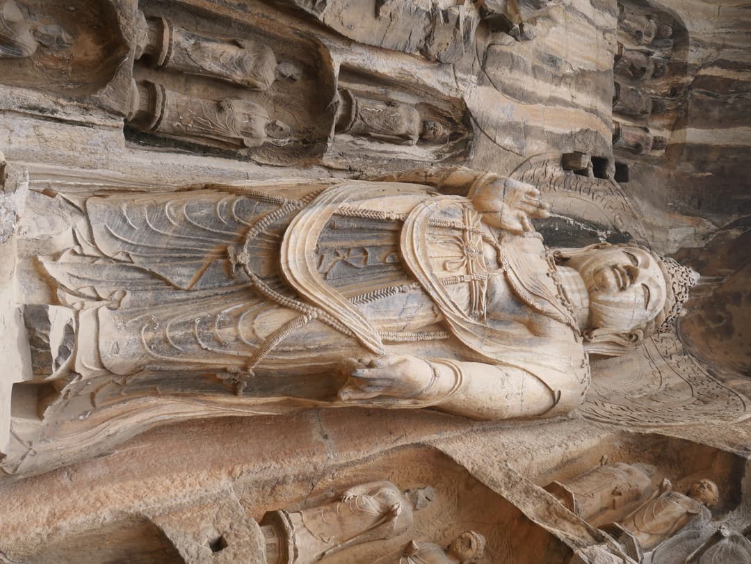 Low-angle view of a carved standing Bodhisattva at the Longmen Grottoes.