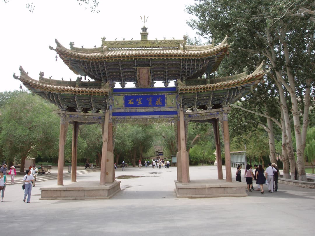 Front view of the ornate wooden paifang archway at the Mogao Caves entrance.