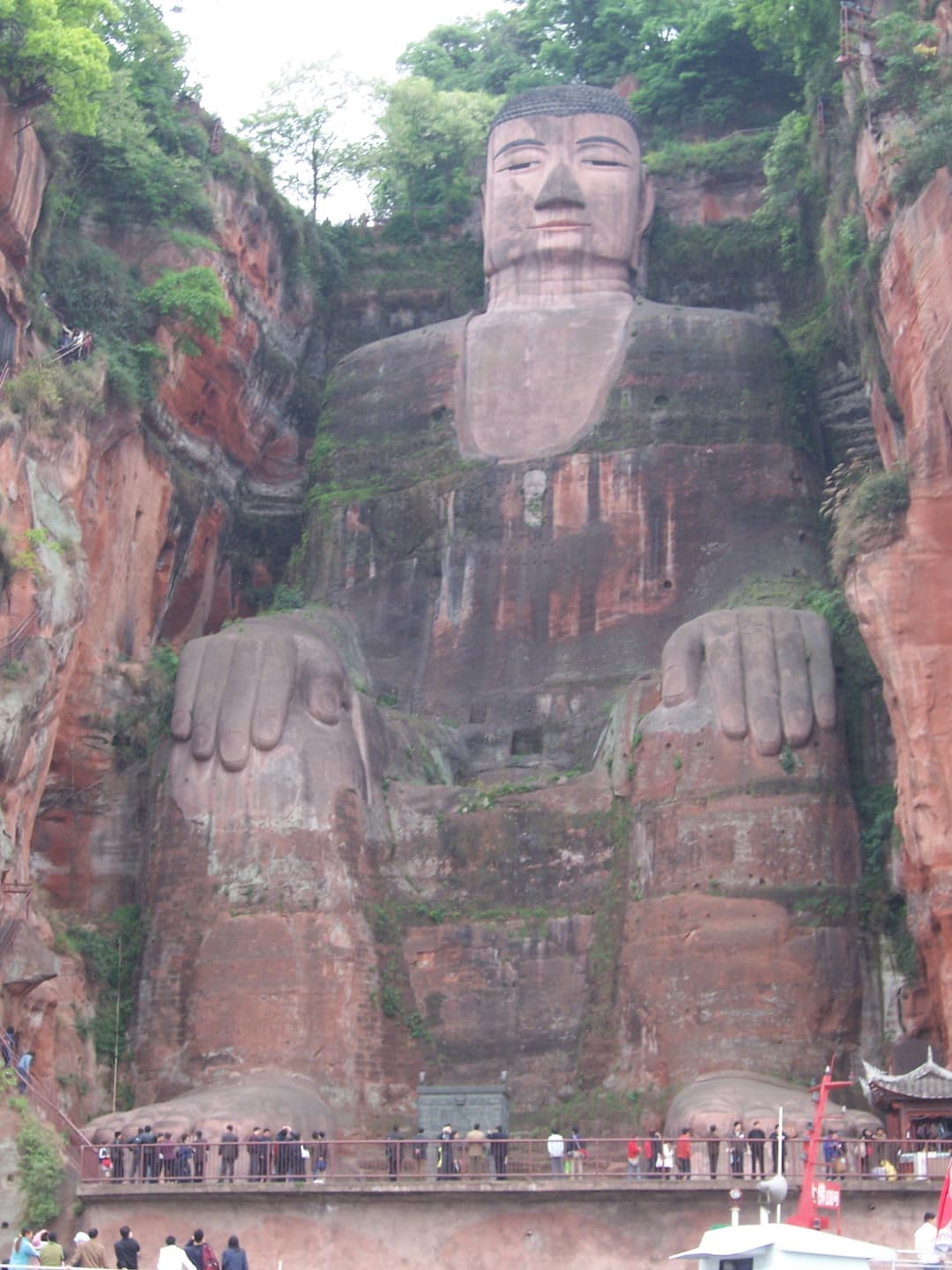 Front view of the Leshan Giant Buddha with visitors at its feet.