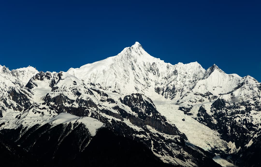 Telephoto view of the snow-capped peak of Mount Kawagarbo under a clear sky.