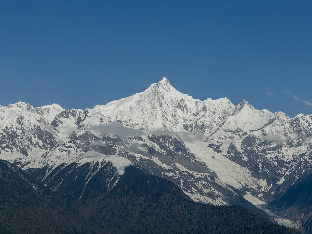 Distant view of snow-capped Mount Kawagarbo peak under a clear blue sky.