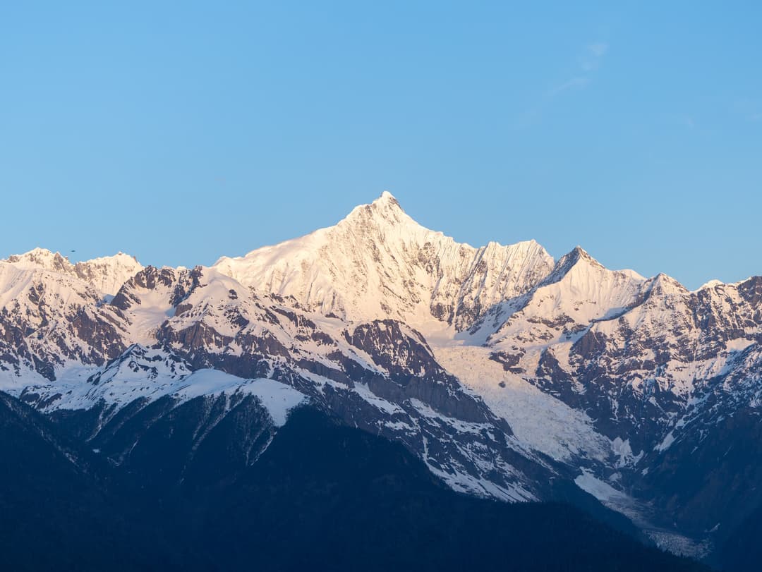 Mount Kawagarbo's snow-capped peak illuminated by golden sunrise light.