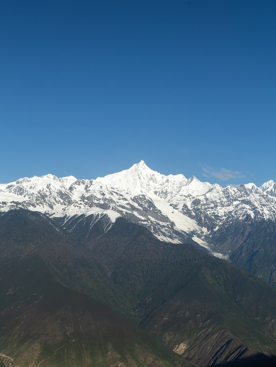 Distant wide-angle view of snow-capped Mount Kawagarbo under clear blue sky.
