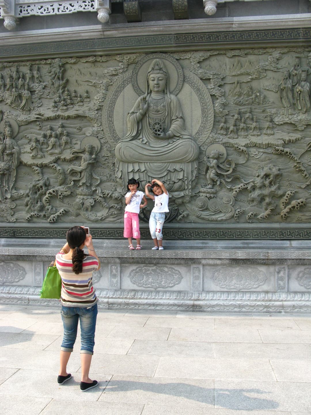 Tourists posing in front of an intricate Guanyin stone relief at Mount Putuo.