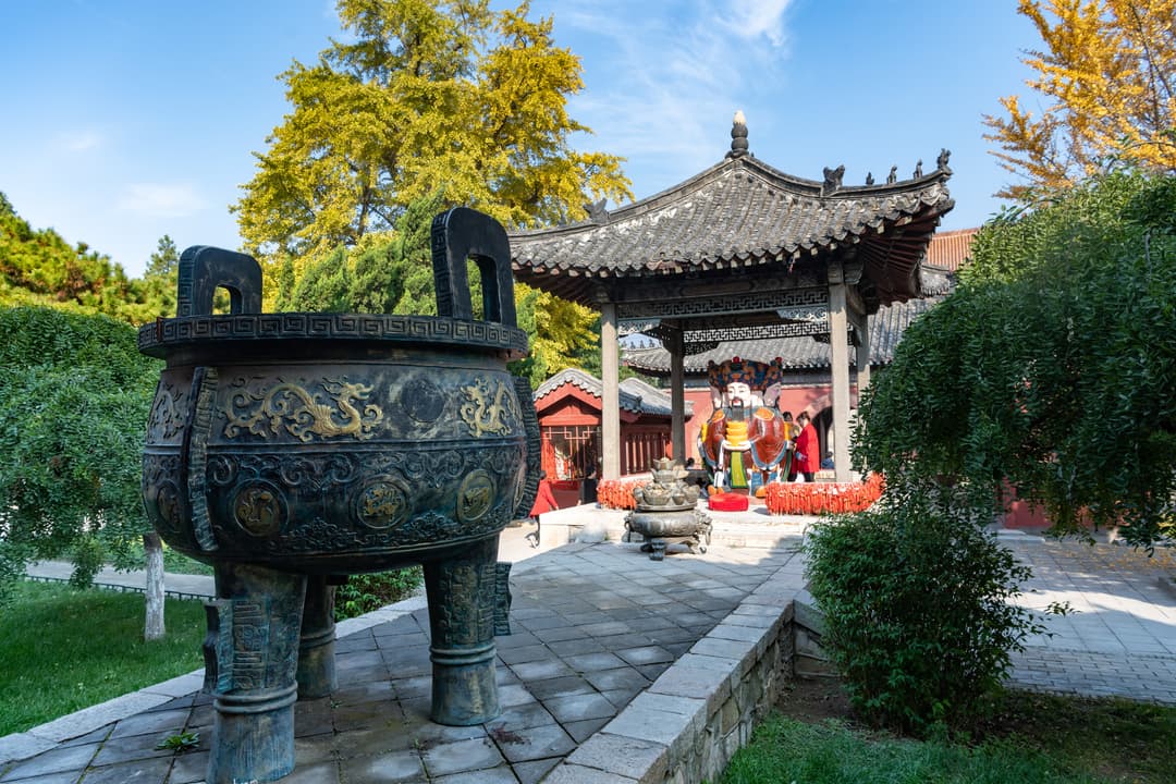 Wide-angle view of a temple courtyard with a large bronze tripod cauldron.