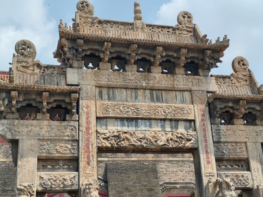 Intricately carved stone paifang archway with dragon reliefs at Mount Tai.