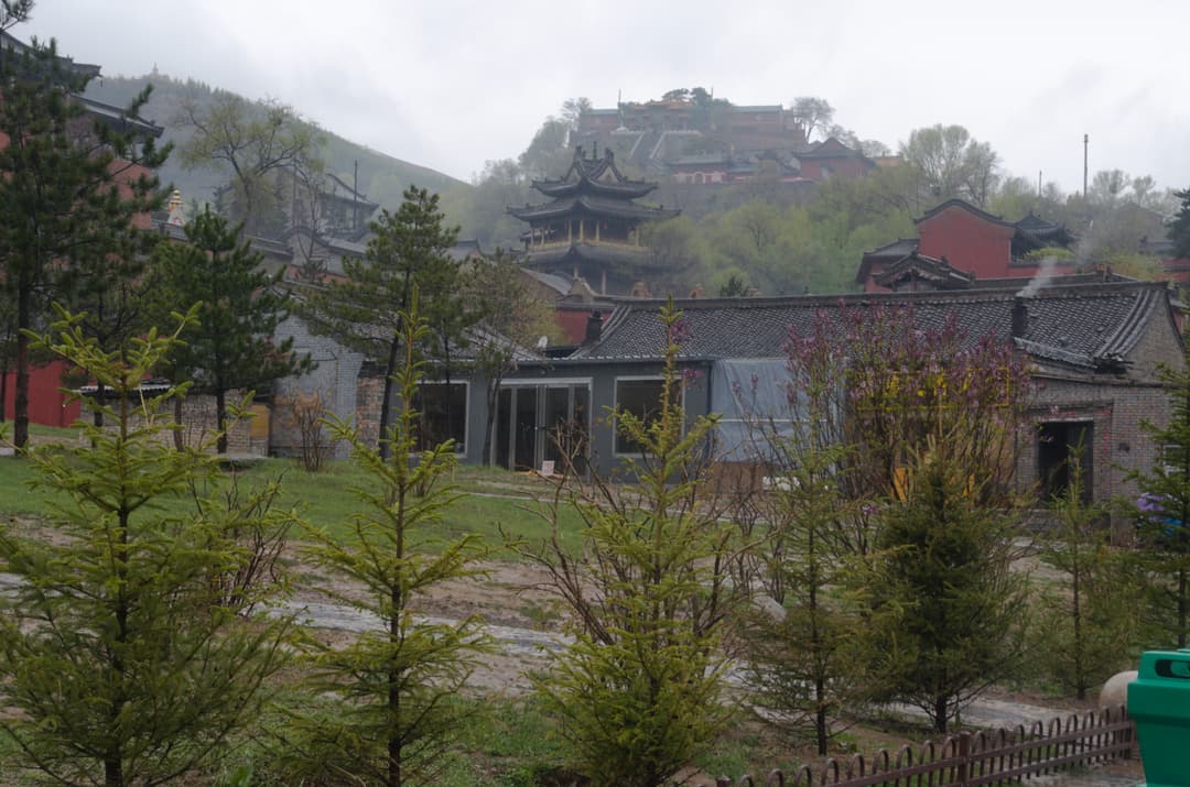 Wide-angle view of misty temple grounds and hillside pagoda at Mount Wutai.
