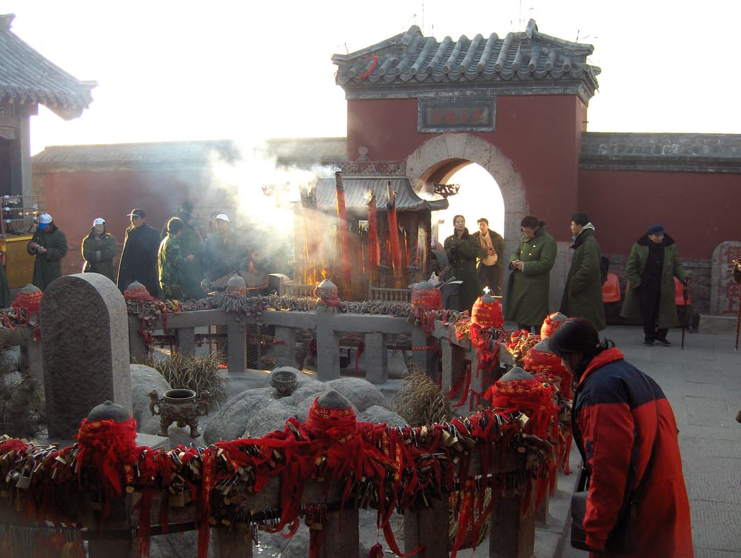 Temple grounds with offerings and smoke from incense, daytime.