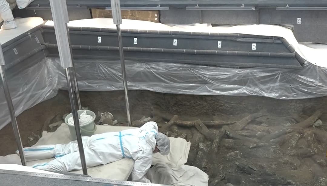 Archaeologist in a protective suit working inside a Sanxingdui excavation pit.