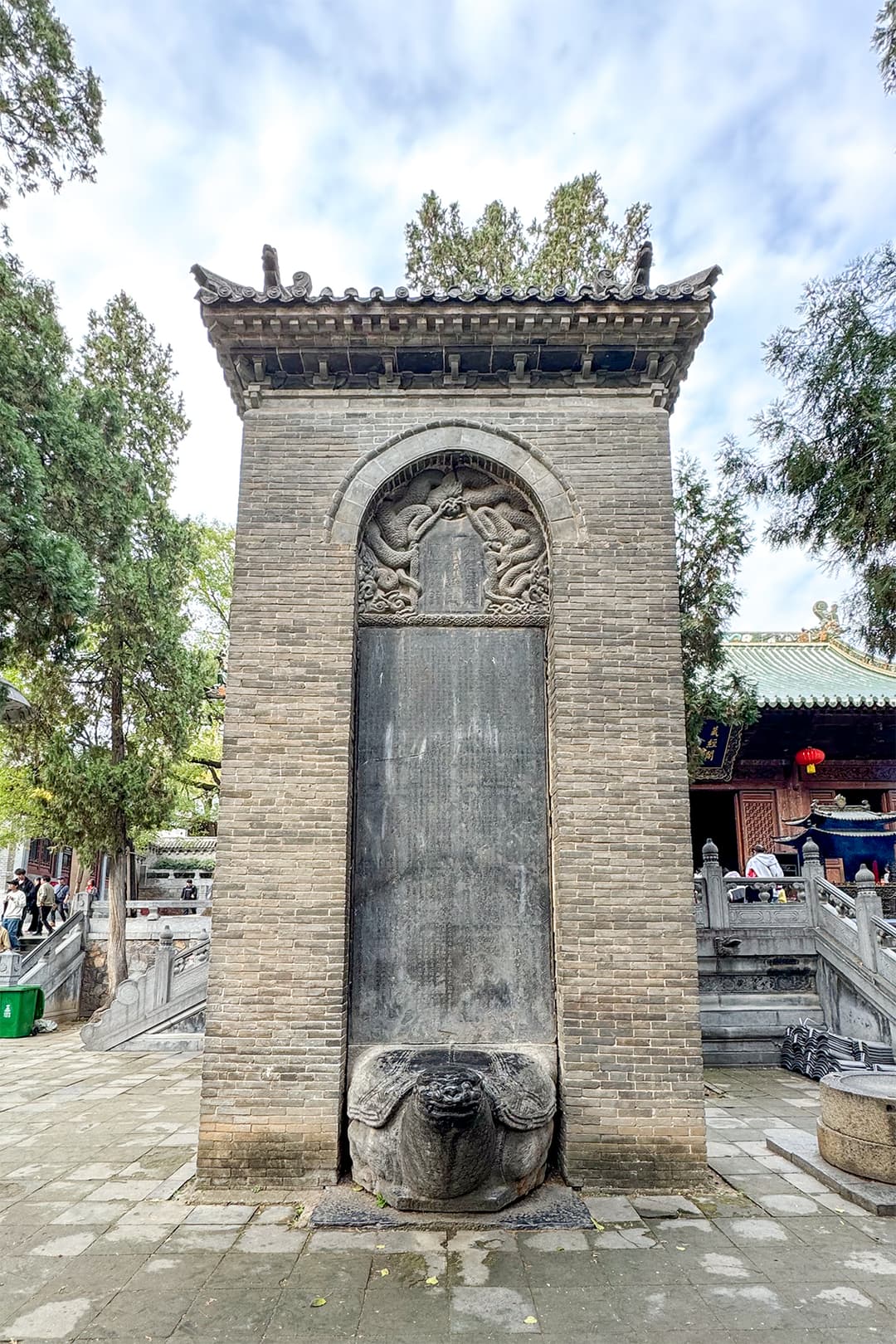 Bixi-borne stone stele inside a brick pavilion in the temple courtyard.