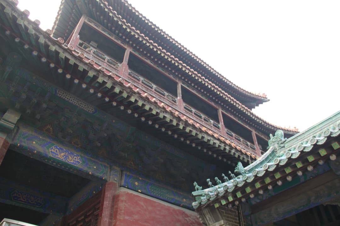 Low-angle view looking up at the painted timber eaves and tiled roofs.